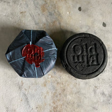 Load image into Gallery viewer, Black Mineral Treatment Shampoo Bar used for the removal of hard water buildup due to well water, wrapped in marbled paper.